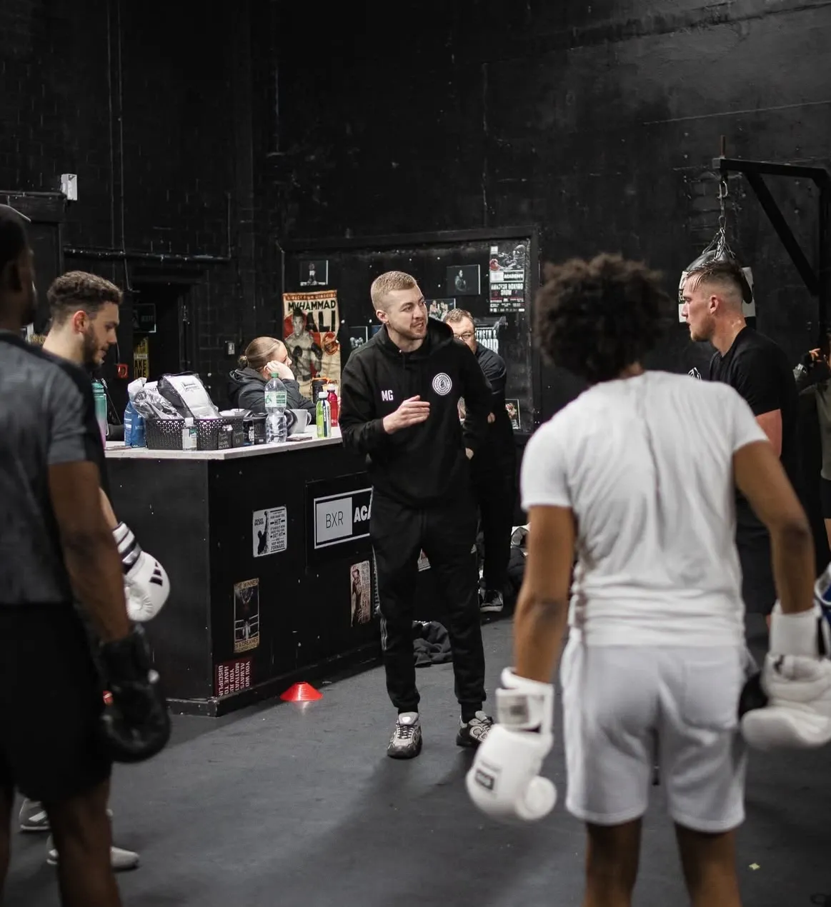 A coach holding pads for a young boxer